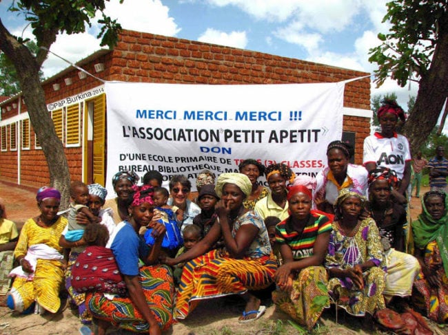 Des habitants au Burkina Faso devant une école construite grâce aux dons récoltés par l'association "Petit à Petit". (document transmis)