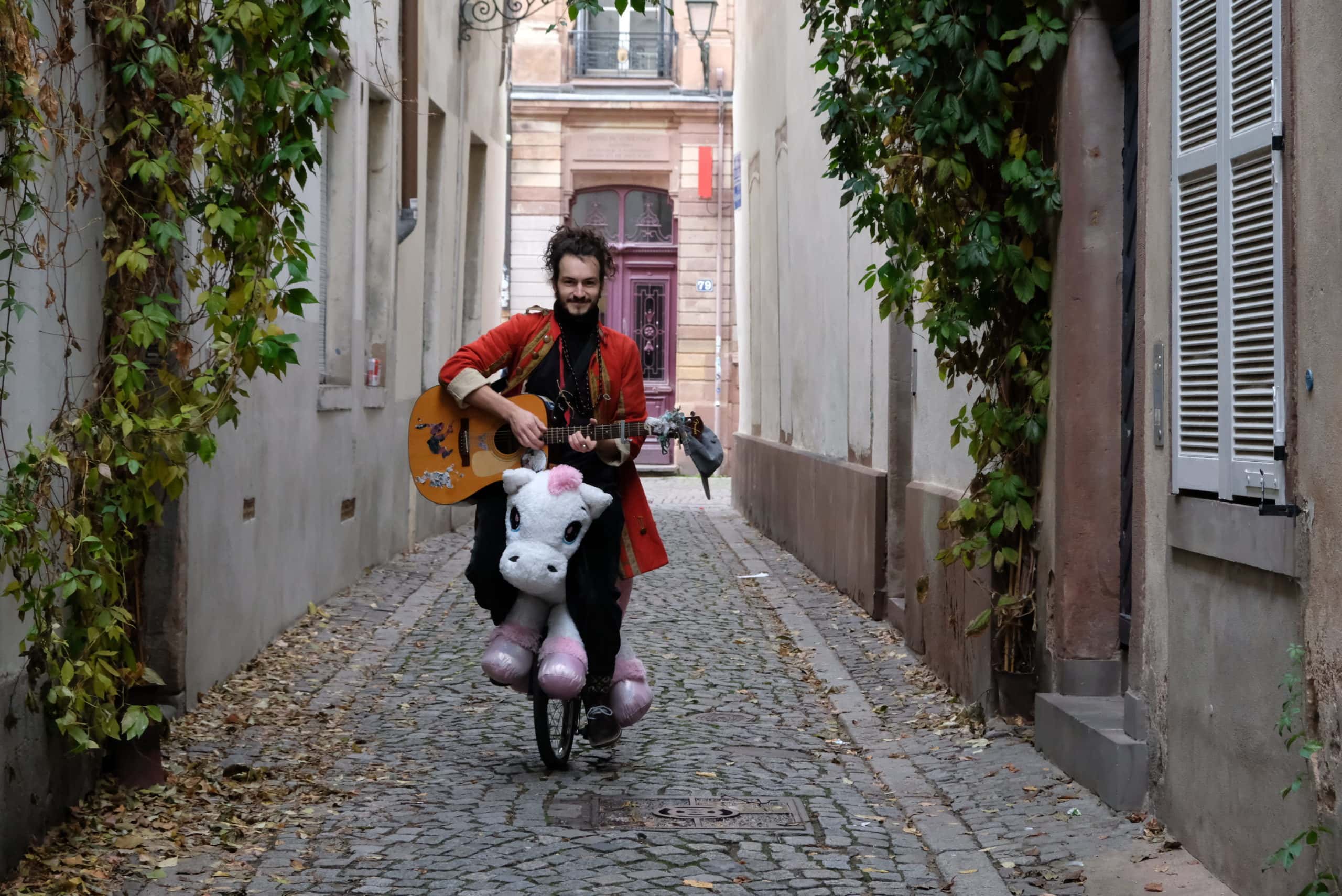 En lutte contre la morosité, Baptiste Schohn joue de la guitare sur un monocycle-licorne