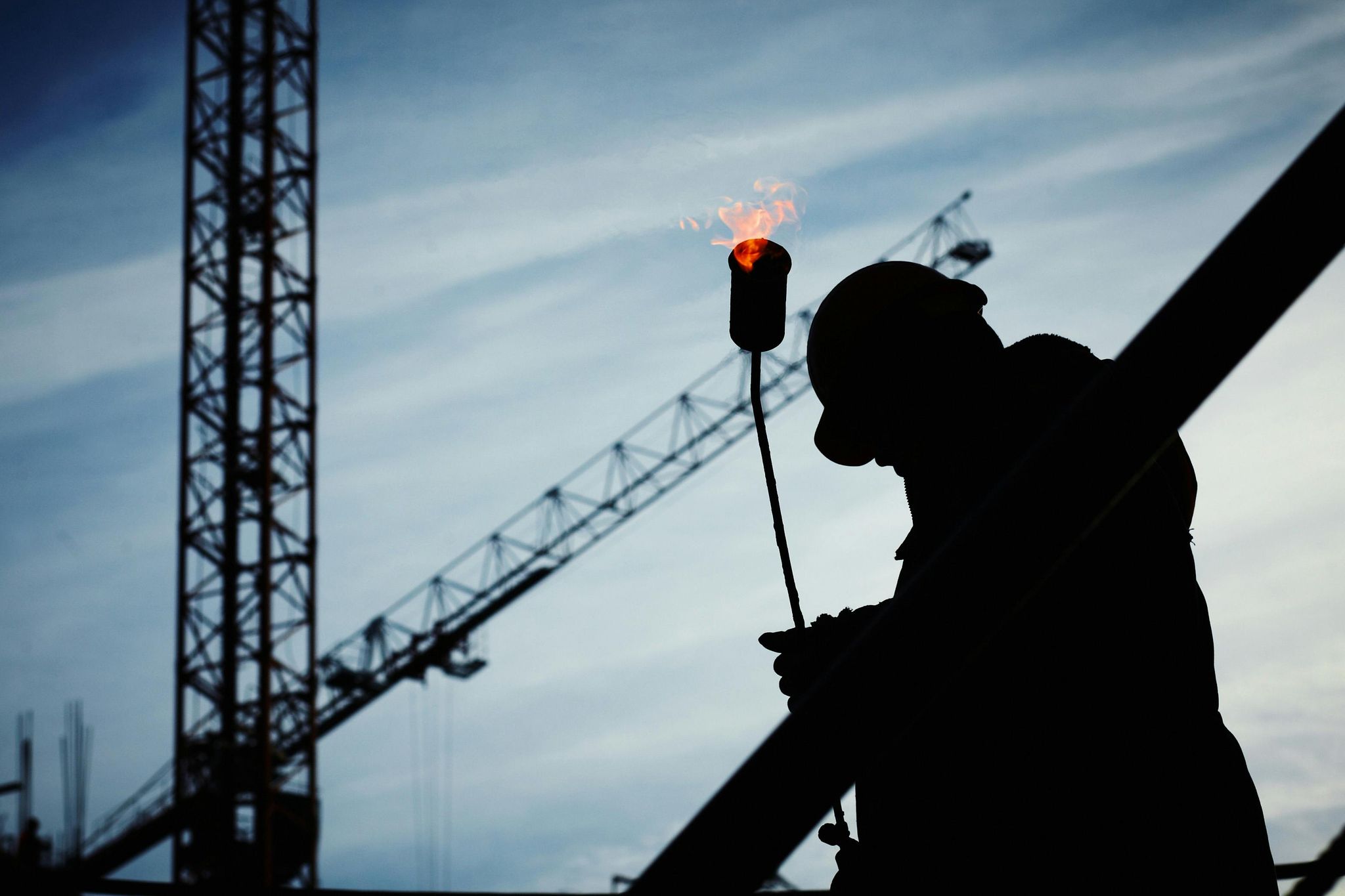 Silhouette d'un homme tenant un lance flammes sur un chantier